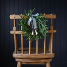 Norfolk & Cypress Mixed Real Touch Mini Wreath, 12" on a chair at Addison West