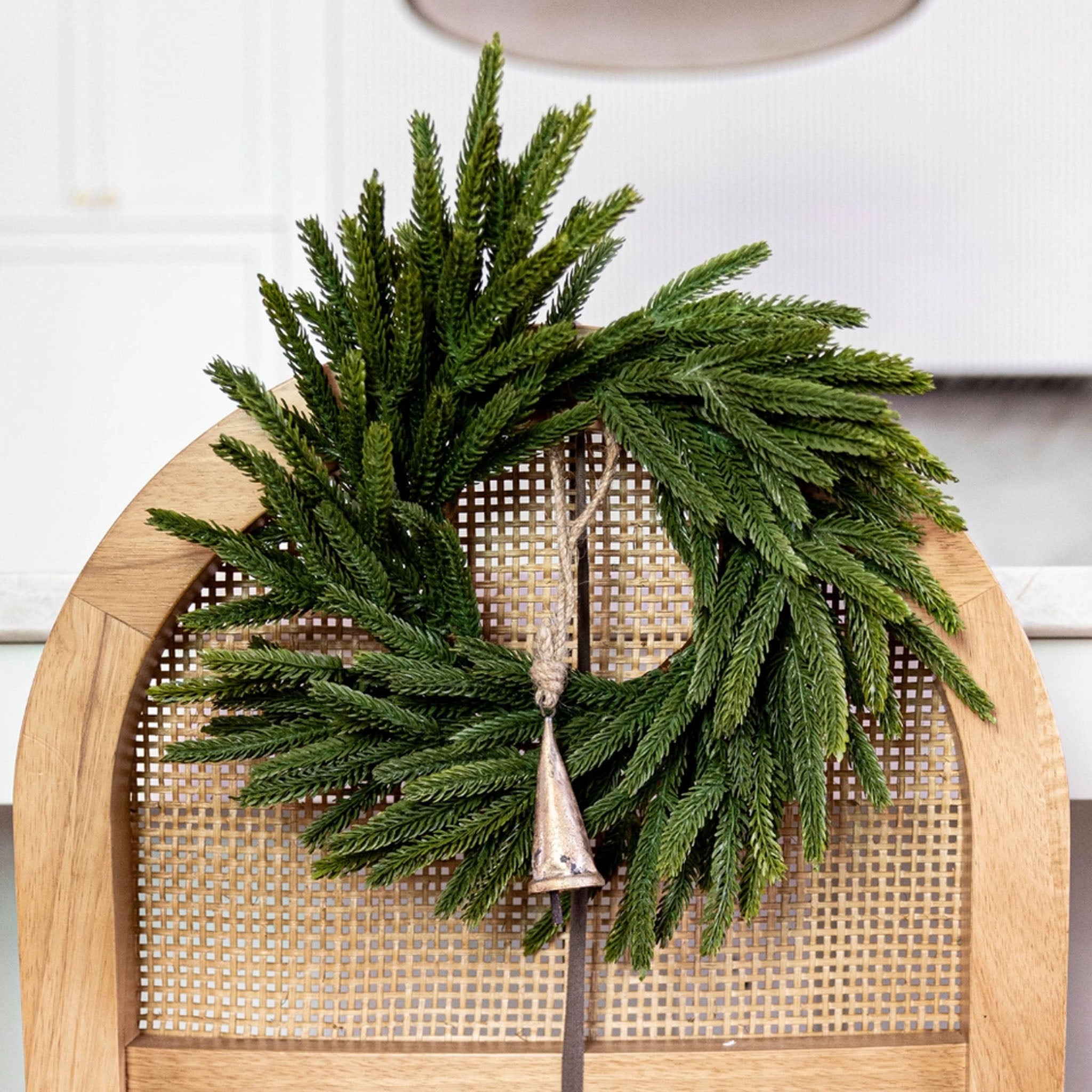 Norfolk & Cypress Mixed Real Touch Mini Wreath, 12" on a chair at Addison West