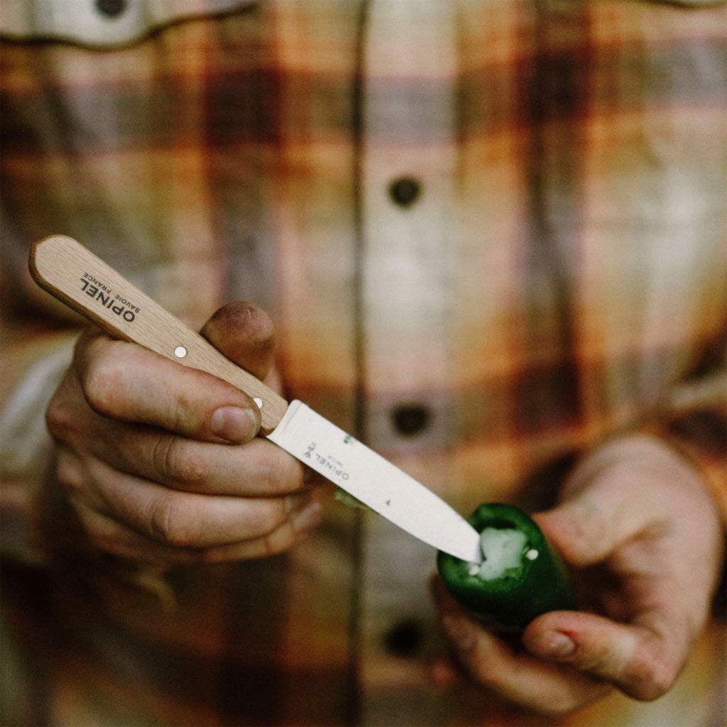 Man in plad shirt using opinel paring knife to carve inside of jalepeno seeds out 