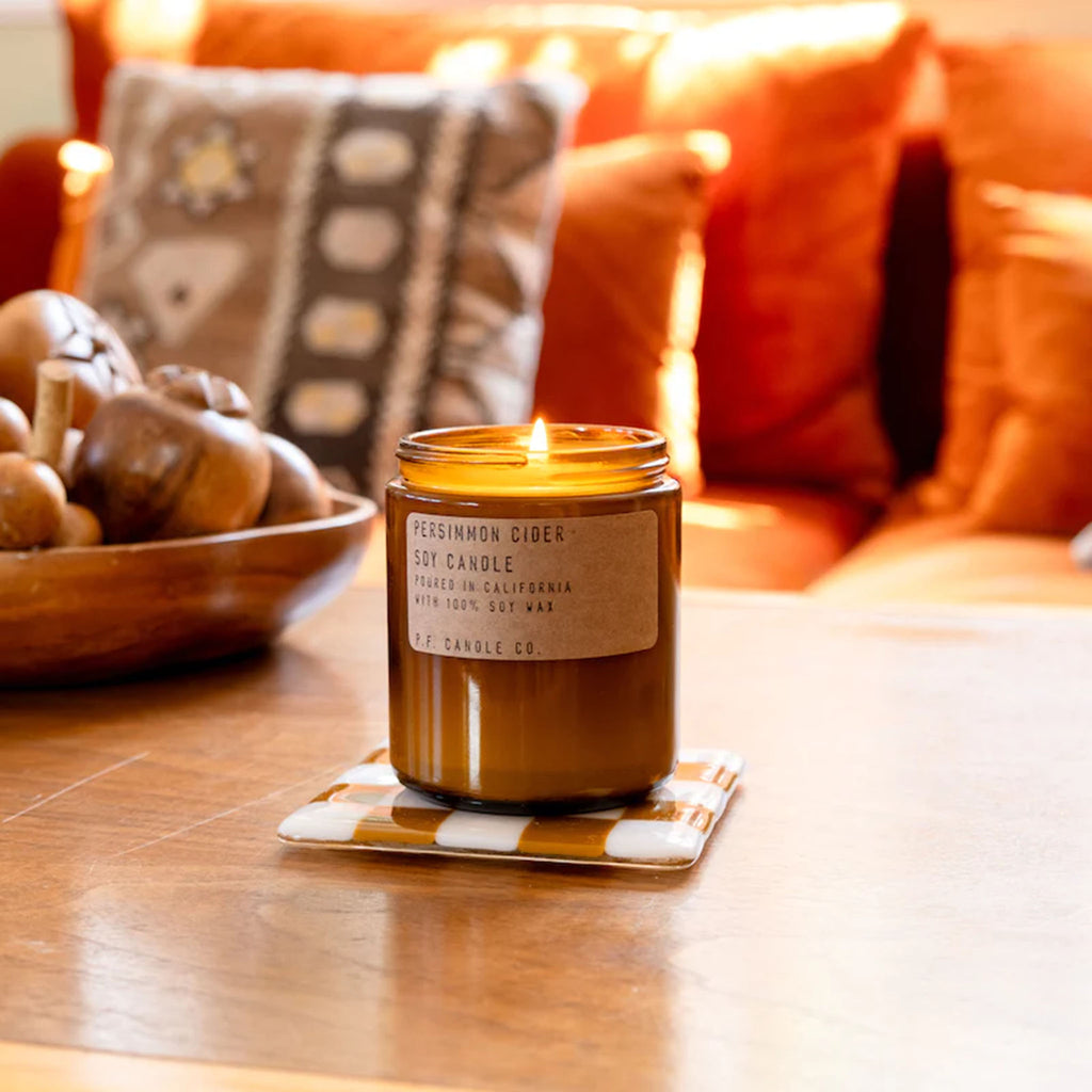 Brown jar of PF Candle Persimmon Cider Candle on a wood coffee table