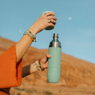 High Camp Parkside Flask in Juniper Green held by a model at Addison West