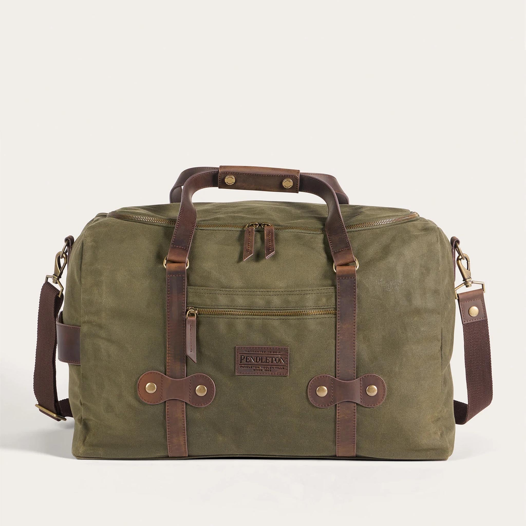 Green duffel bag with brown leather straps and handles on a white background