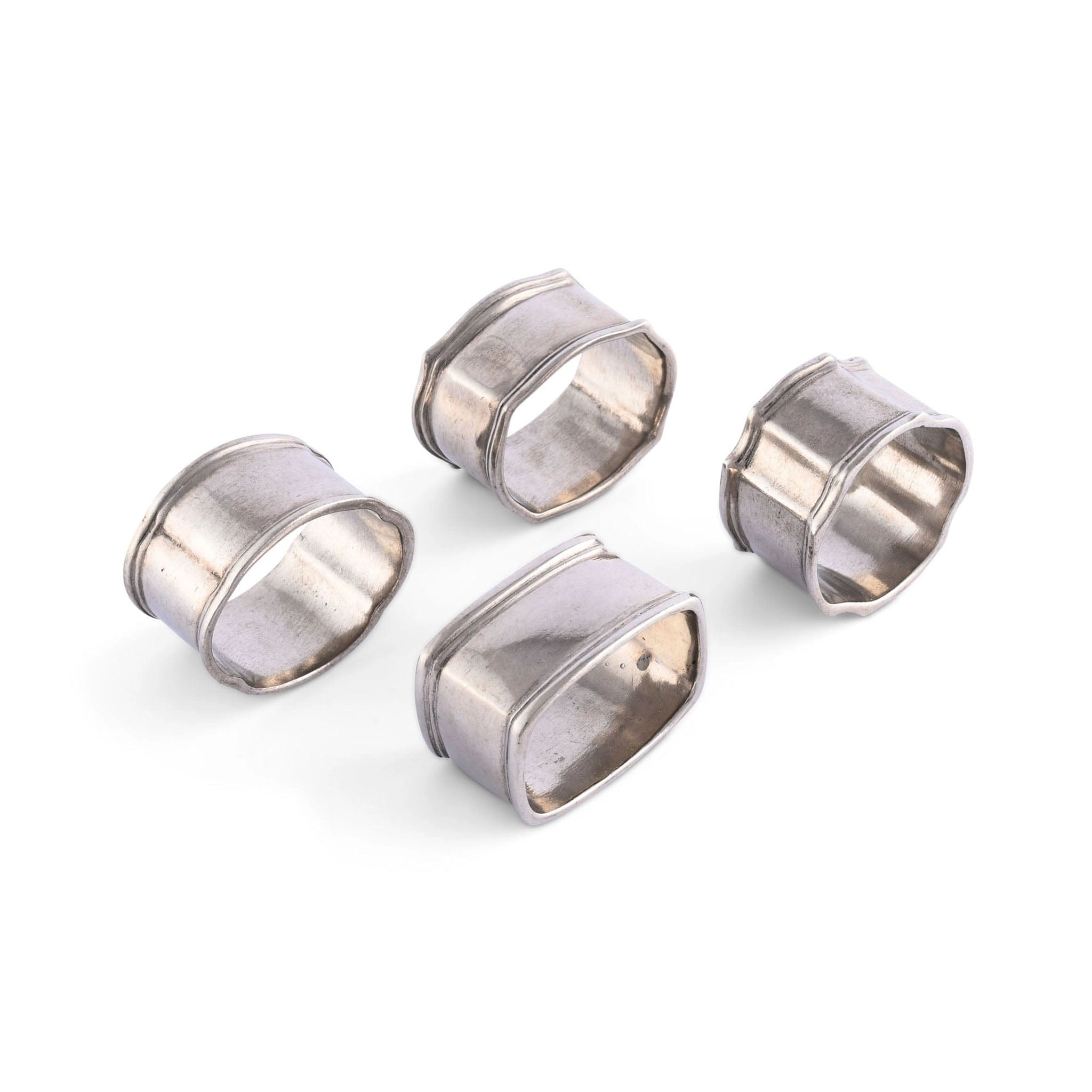 Set of four pewter napkin rings on a white background