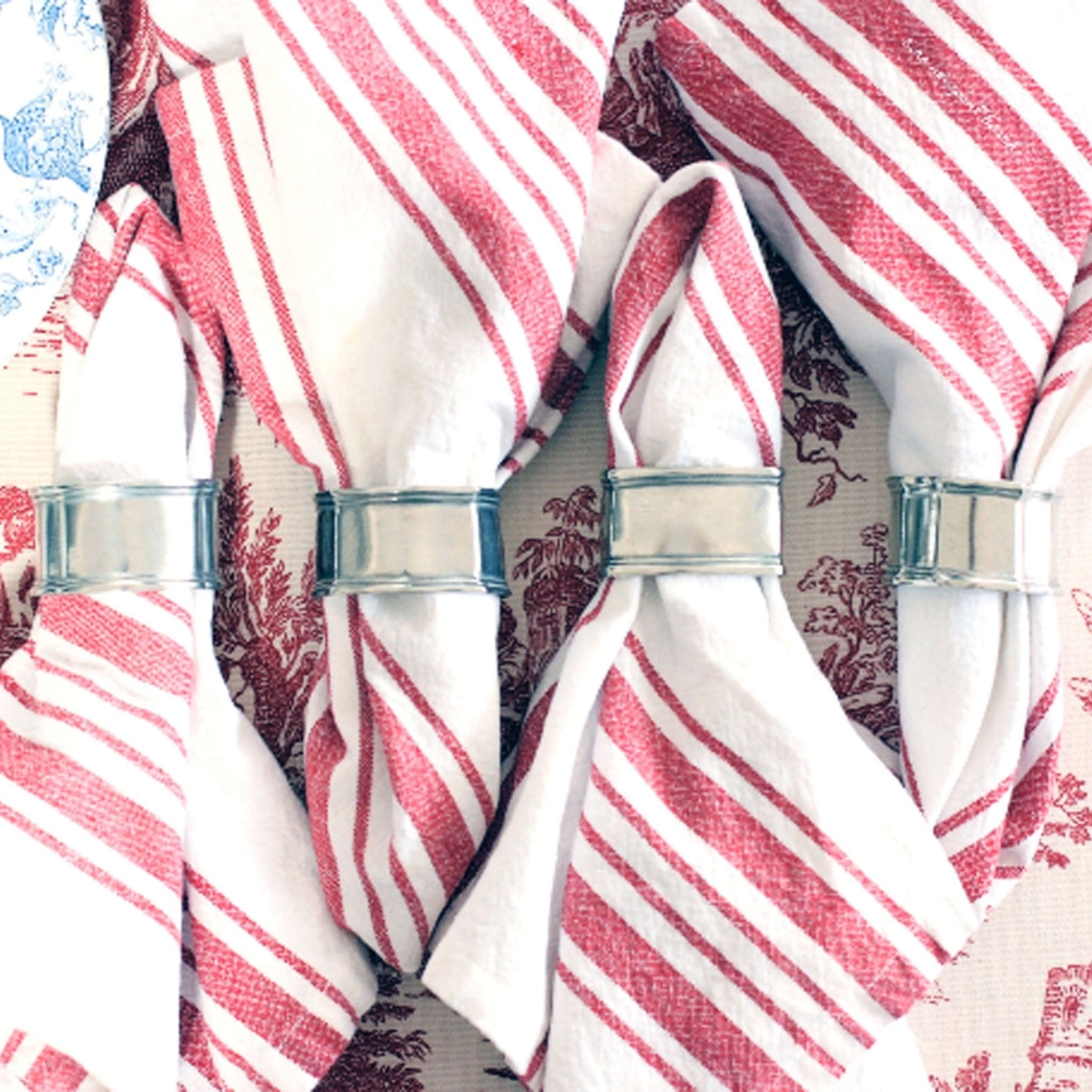 Red and white napkins with four pewter napkin rings. 