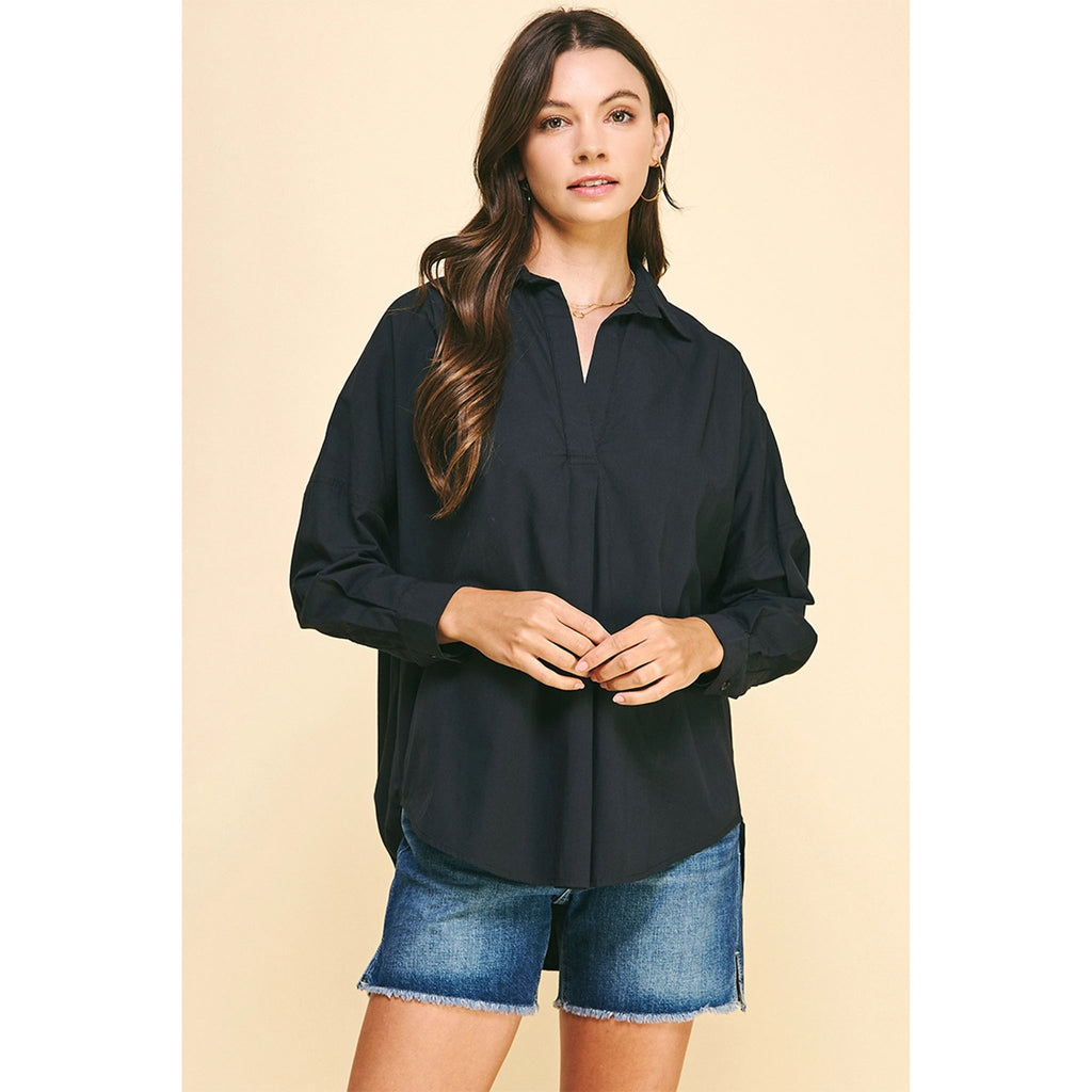 Brunette model wearing jean shorts and black boots and black drop shoulder long sleeve shirt 