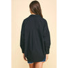 Brunette model wearing jean shorts and black boots and black drop shoulder long sleeve shirt 