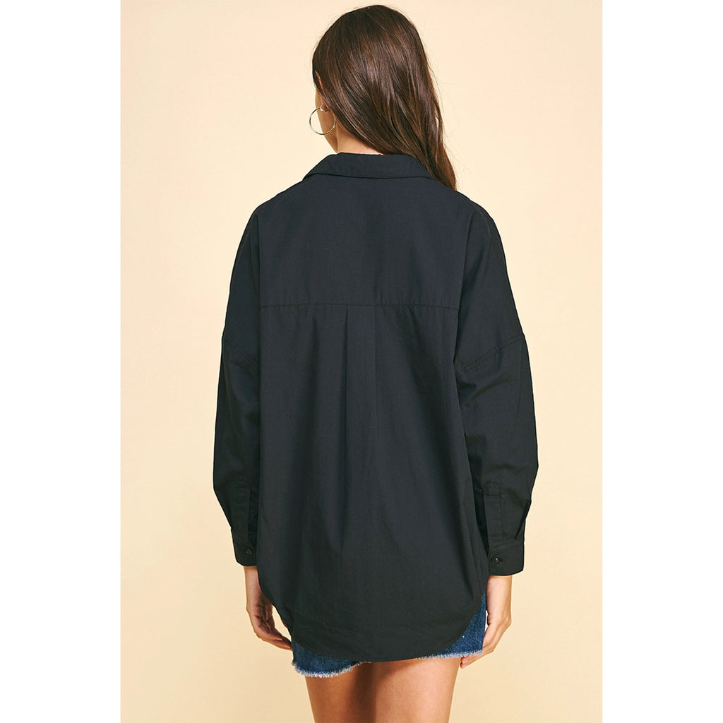 Brunette model wearing jean shorts and black boots and black drop shoulder long sleeve shirt 