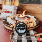 Fire pit with marshmallows, cookies, and a City Bonfires branded container on a checkered tablecloth.