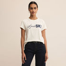 Person wearing a white t-shirt with 'Apres Ski' text on a beige background