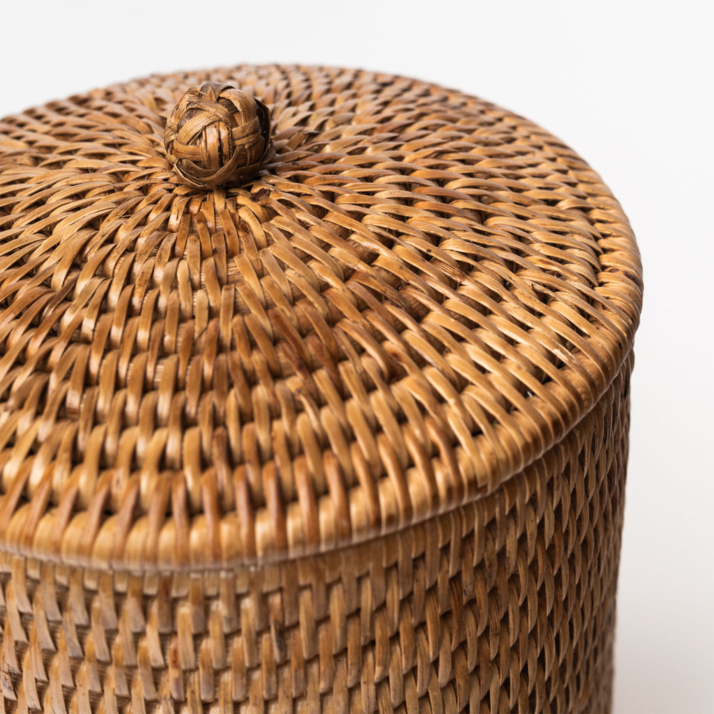 Rattan toilet paper holder with lid on a white background