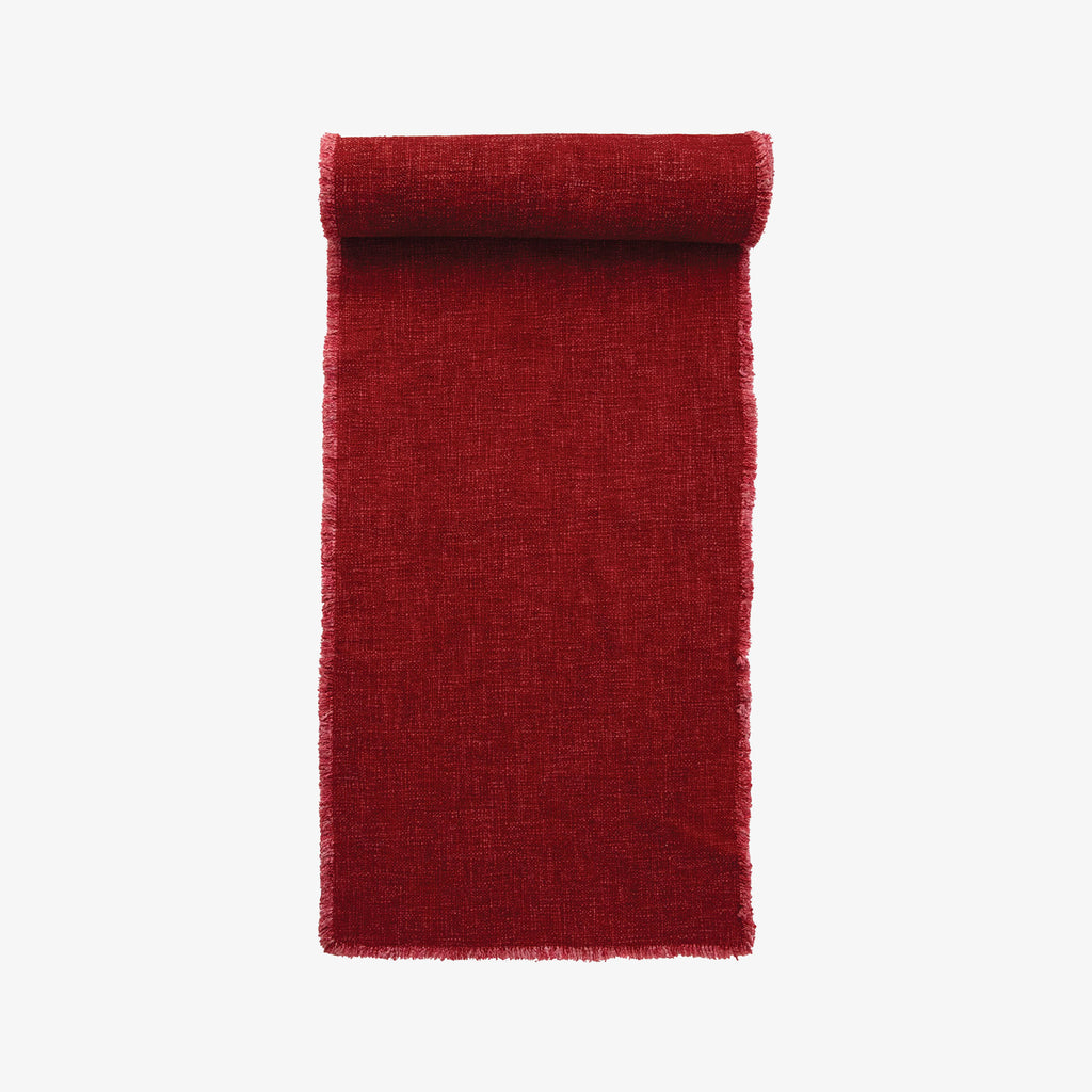 Red table runner with frayed edges on a white background