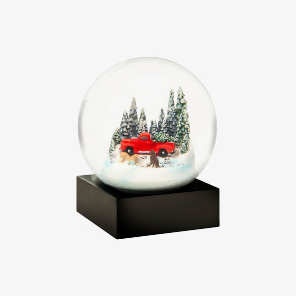 Snow globe with pine trees and red vintage truck and two dogs on a white background