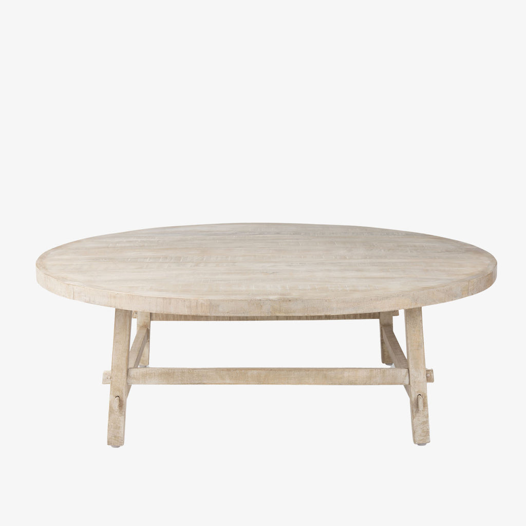Whitewashed wood round coffee table with square dowel legs and bracing on a white background