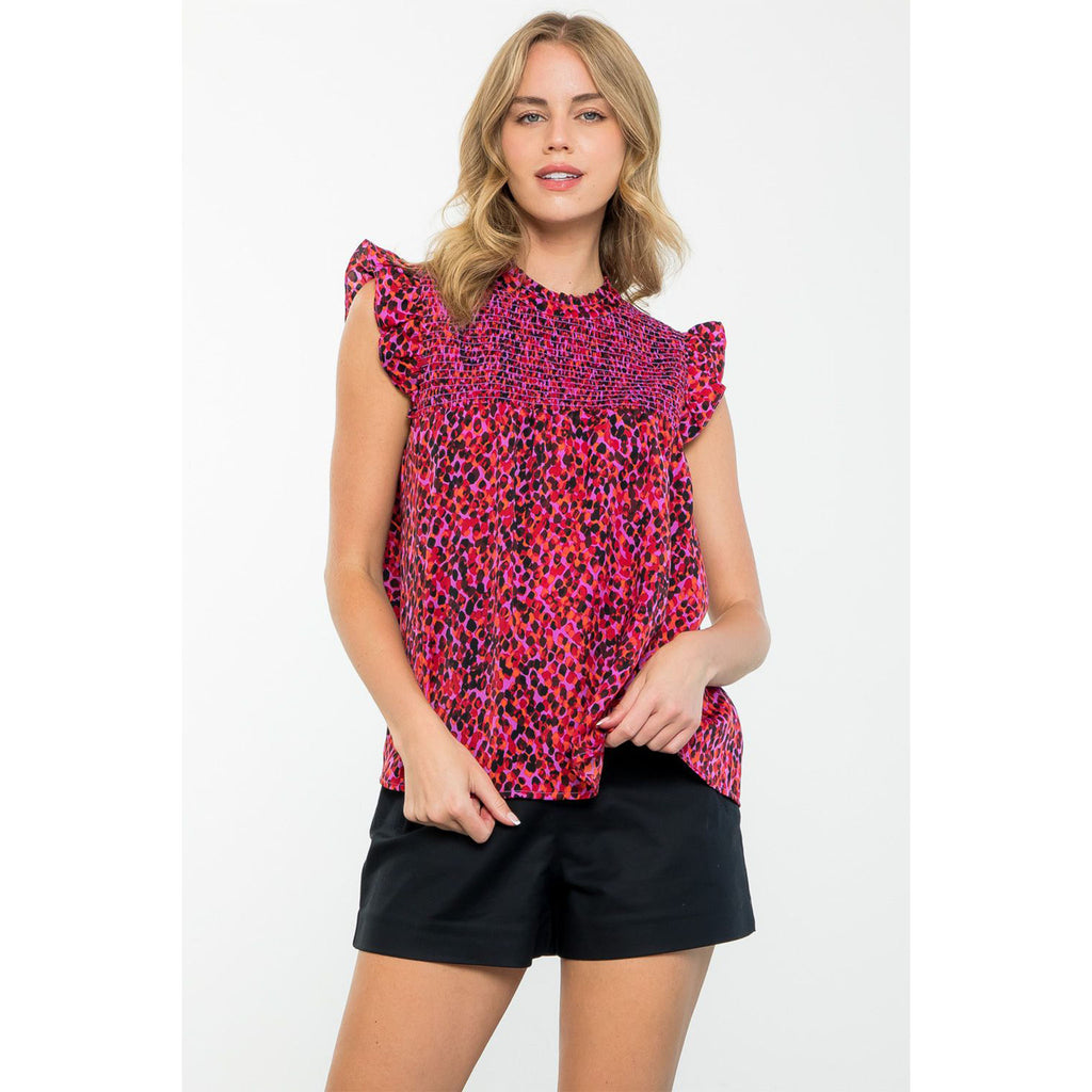 Blond model wearing THML Ruffle Sleeve Smocked Top in fuschia and purple in front of a white wall