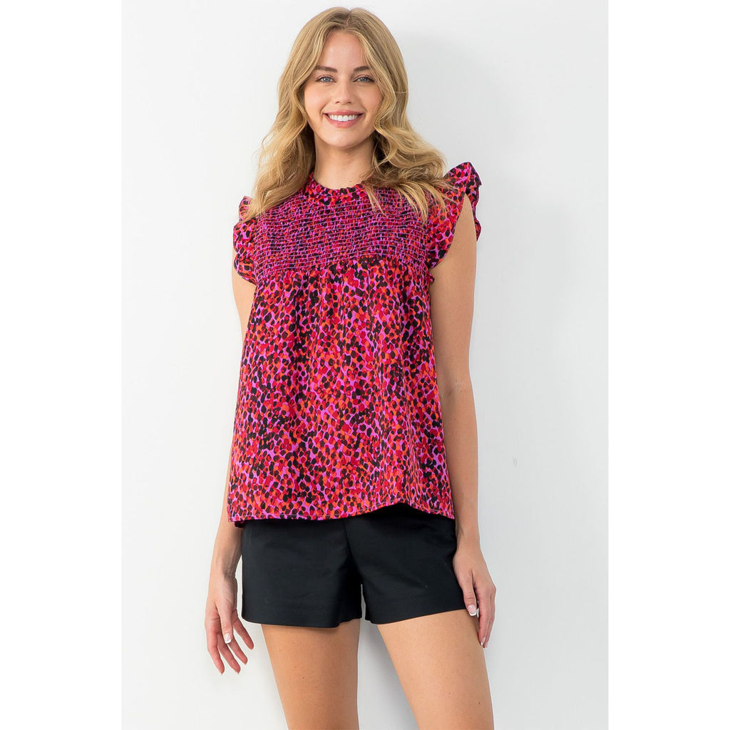 Blond model wearing THML Ruffle Sleeve Smocked Top in fuschia and purple in front of a white wall