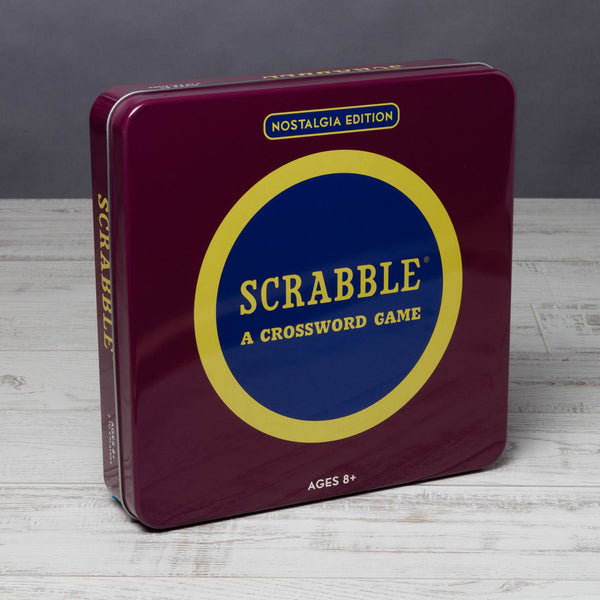 Burgundy scrabble game box in metal tin on a wood surface