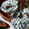 Wood tray with plates and serving utensils and white napkins with pine trees on them