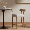 Four Hands Simone Counter Table in Antique Rust with two chairs in a dimly lit space with upholstered counter chair 