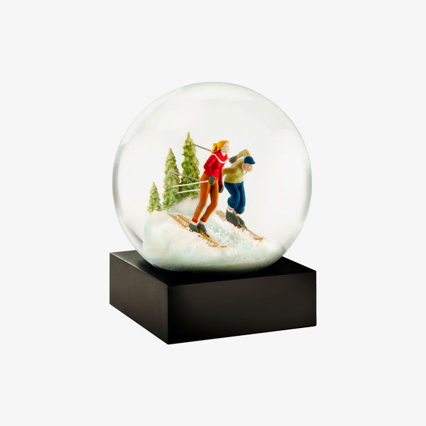 Snowglobe with two skiers and pine trees on a white background