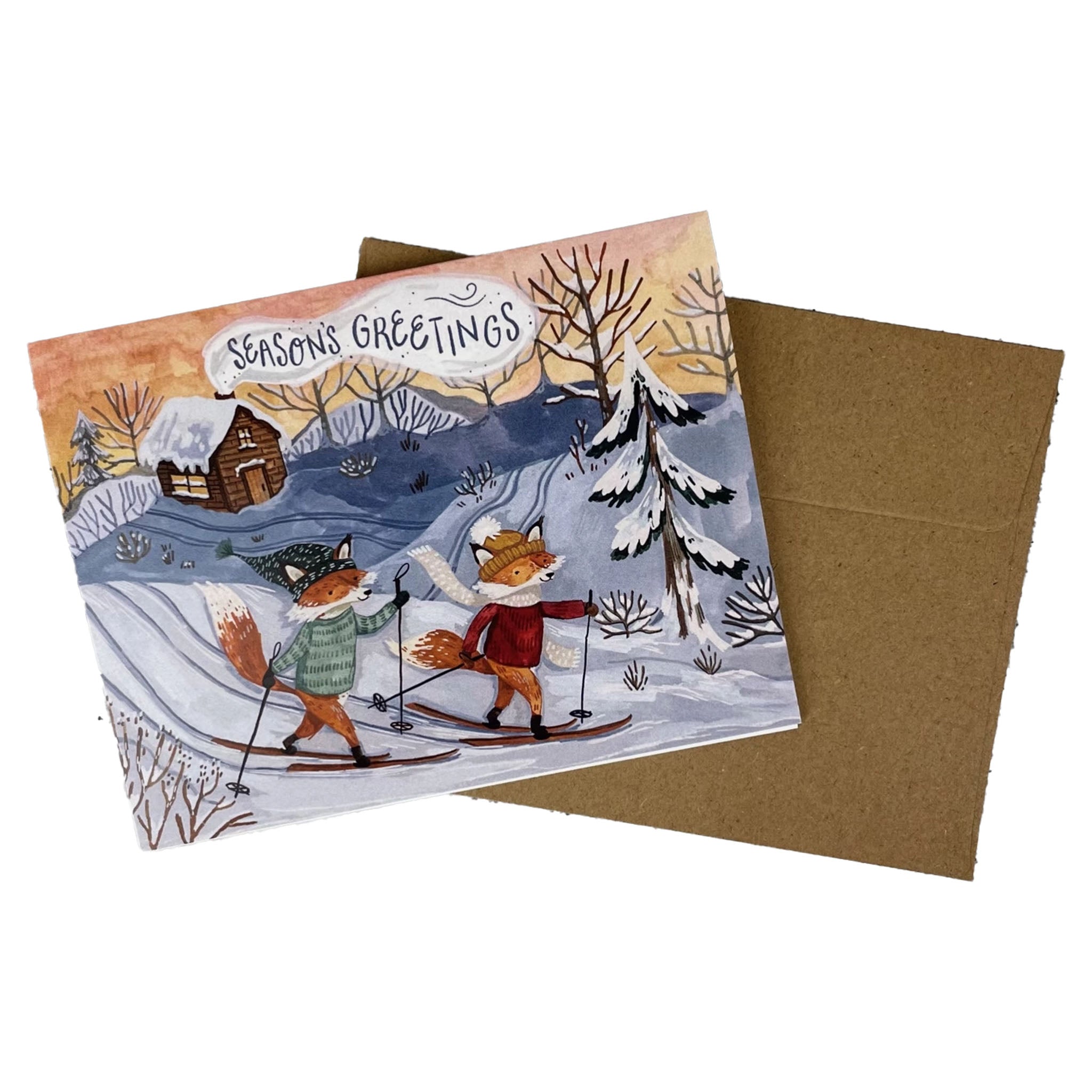 Seasons Greetings card with two foxes skiing in a snowy landscape, featuring a brown envelope.