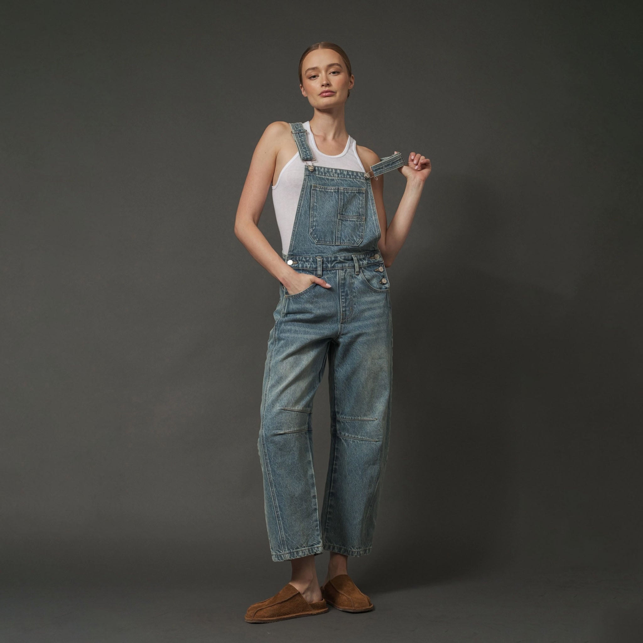 Woman wearing Aaron & Amber Relaxed Fit Overalls in Denim on a dark background