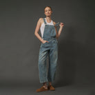 Woman wearing Aaron & Amber Relaxed Fit Overalls in Denim on a dark background