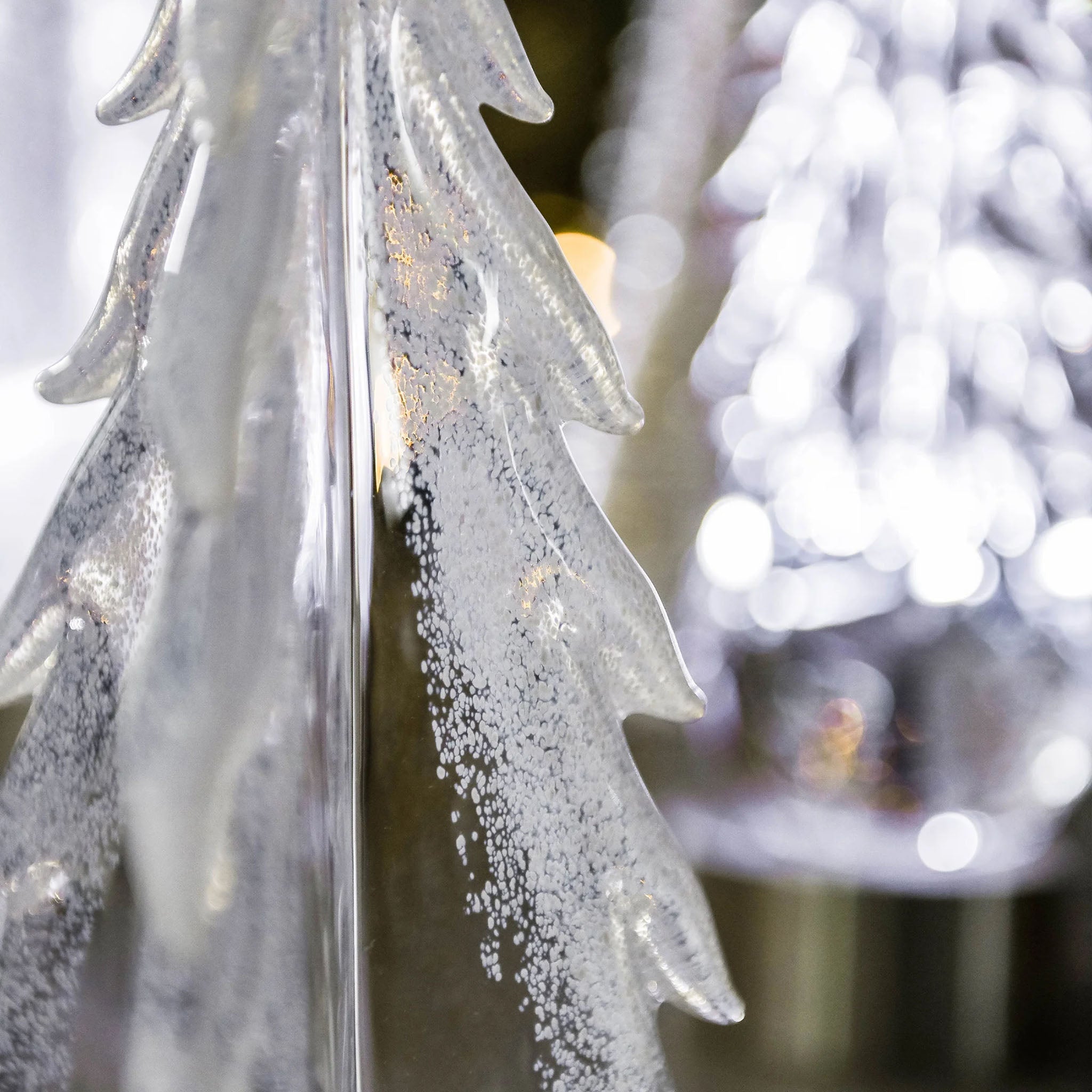 Close up of Simon Pearce Snowy Branches Evergreen Glass Tree on a table at Addison West