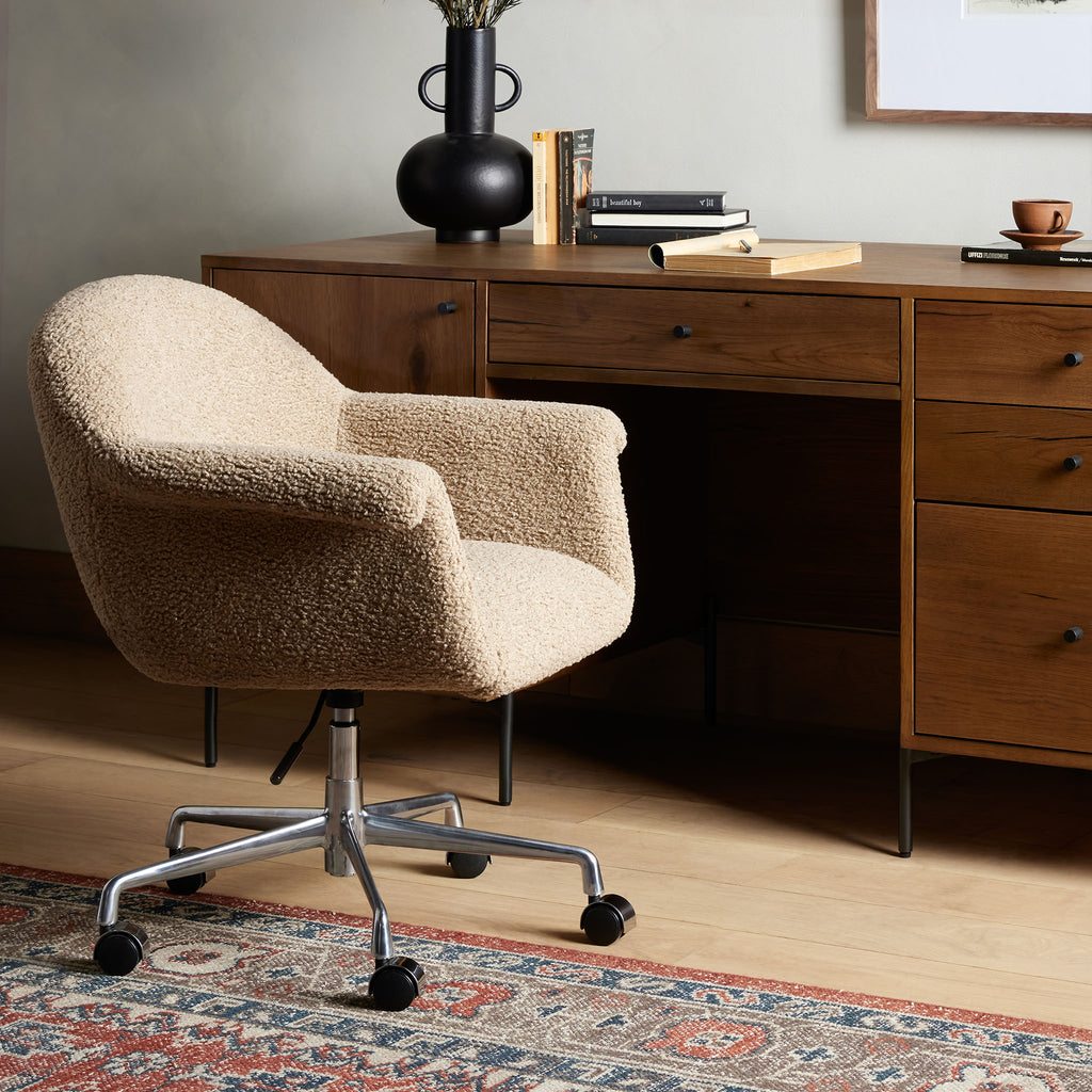 Four Hands Suerte Desk Chair in Camel Sheepskin in an office with a wood desk and tribal rug
