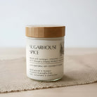 Scented candle jar labeled 'Sugarhouse Spice' on a textured surface