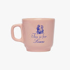 Pink mug with blue text and graphics on a white background