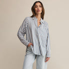Woman wearing Z supply perfect line blue and white striped shirt against a beige background
