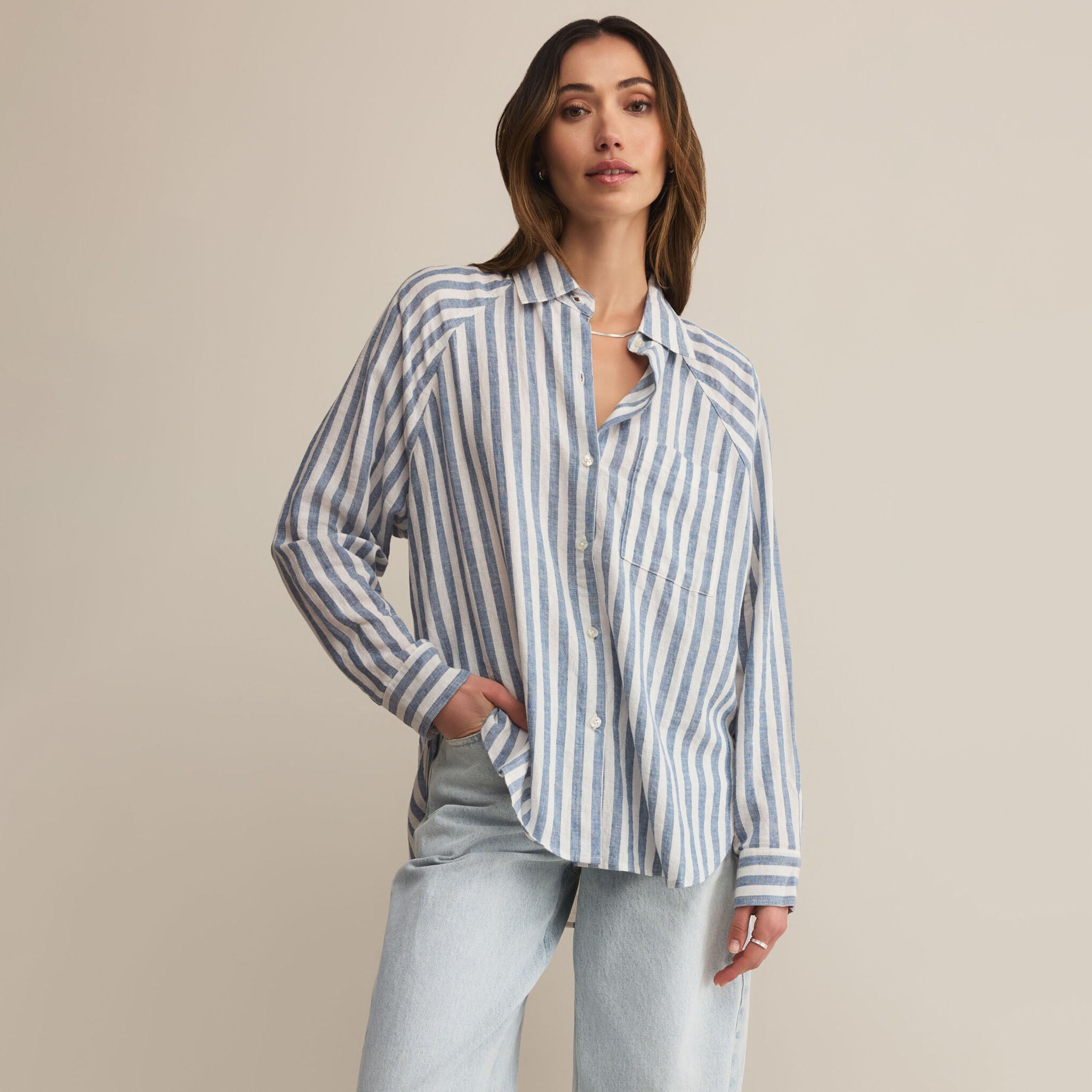 Woman wearing Z supply perfect line blue and white striped shirt against a beige background