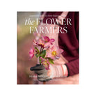 Front cover of book titled The Flower Farmers with a woman in a pint apron holding pink flowers.