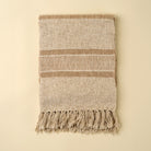 Tulum Striped Throw in Clay on a beige background at Addison West
