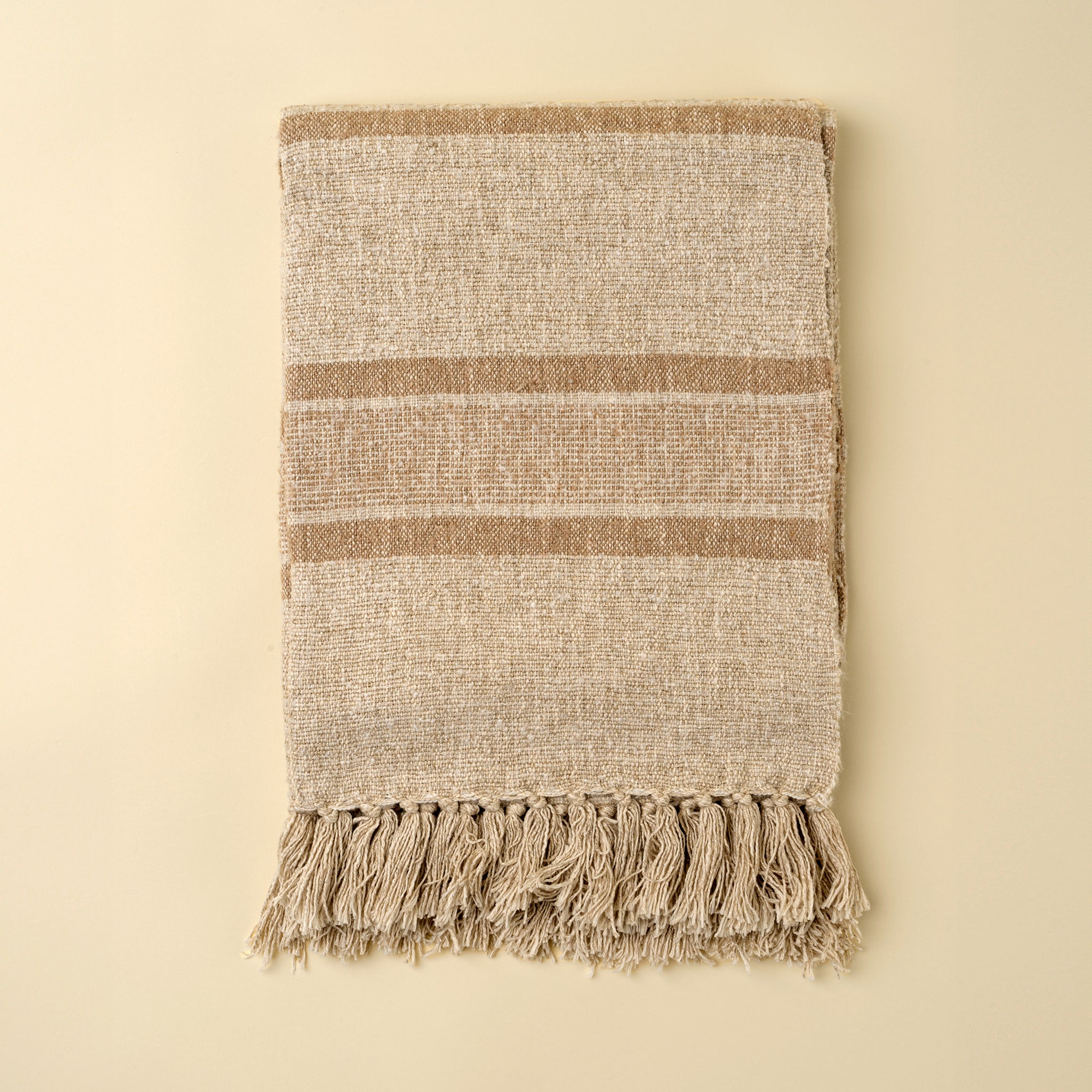 Tulum Striped Throw in Clay on a beige background at Addison West