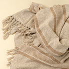 Tulum Striped Throw in Clay on a beige background at Addison West