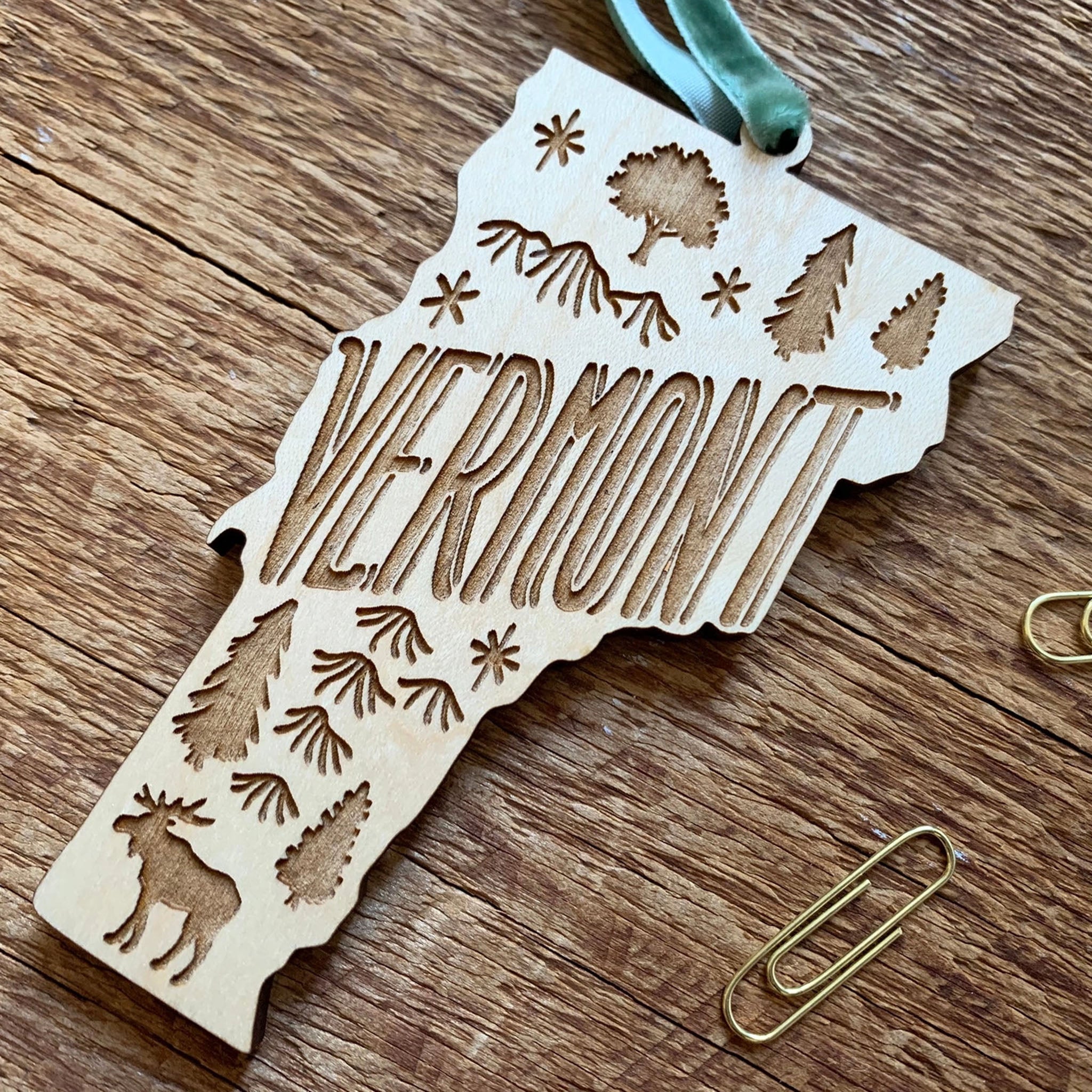 State of Vermont shaped laser cut wood Ornament on a wood surface