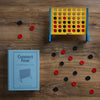 Vintage Bookshelf Edition Connect Four on a wood table displaying the game components 
