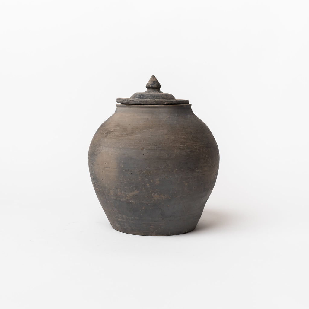 Black terracotta lidded jar on a white background