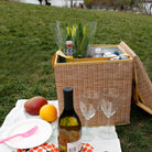 Wicker Picnic Cooler Seat on grassy lawn with wine and glasses 