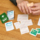 Person using Wilderness First Aid Kit on a wood table