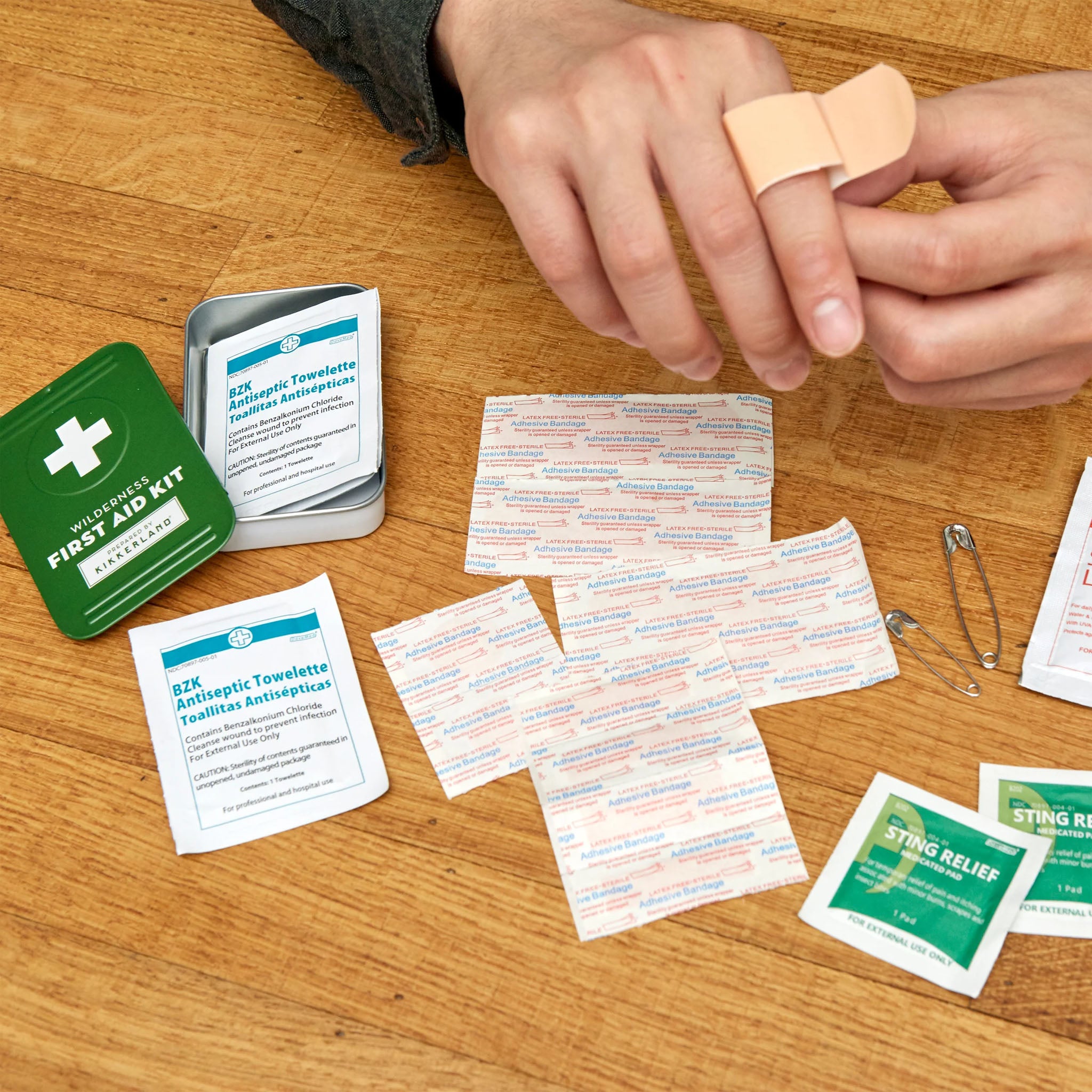Person using Wilderness First Aid Kit on a wood table