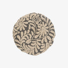 A round grey throw pillow with a hand-embroidered floral pattern.