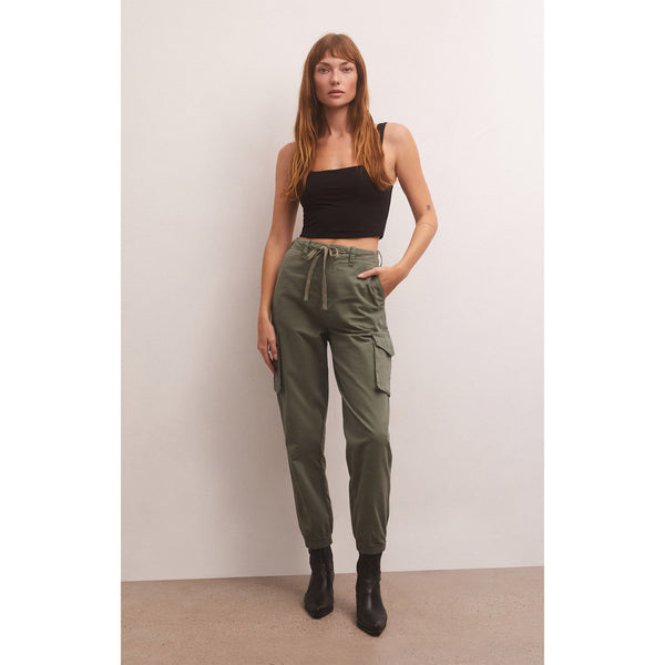 Model wearing black tank top and Z Supply Andi Twill Pant in Evergreen with black booties in front of a beige wall