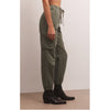 Model wearing black tank top and Z Supply Andi Twill Pant in Evergreen with black booties in front of a beige wall