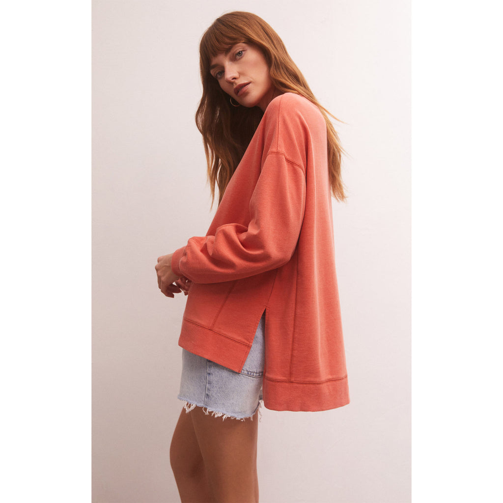 Model wearing Z Supply Modern Weekender in Lava with cut off jean shorts in front of a white wall
