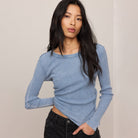 Woman wearing a blue long-sleeve top against a plain background
