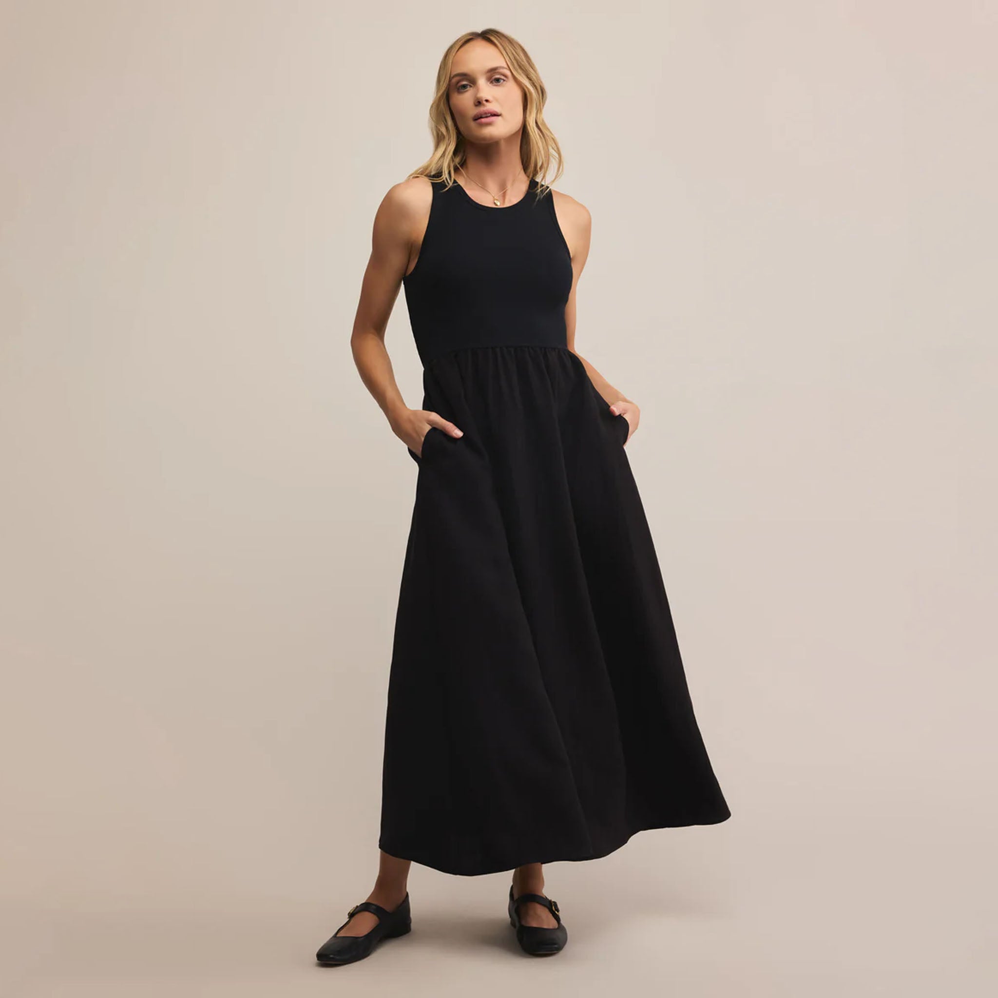 Woman wearing a black sleeveless dress against a beige background