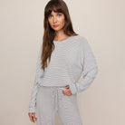 Woman wearing a striped long-sleeve top and pants on a beige background