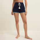 Person wearing navy shorts with white trim on a beige background